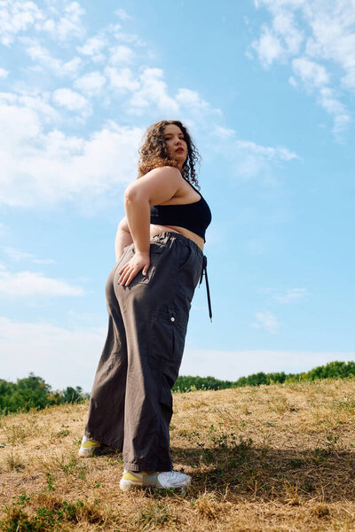 Радостная женщина обнимает природу, грациозно стоя в ярком зеленом поле под голубым небом.