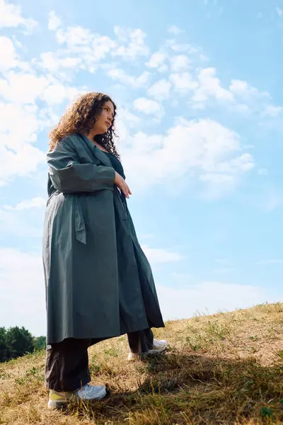 stock image A confident plus size woman enjoys nature while standing in a scenic field on a sunny day.