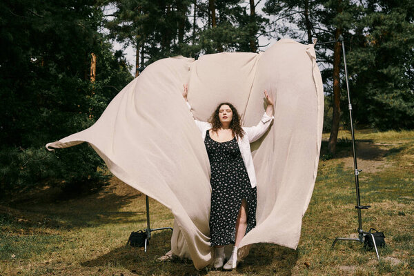 A beautiful plus size woman joyfully poses in a sunlit field, celebrating natures beauty.