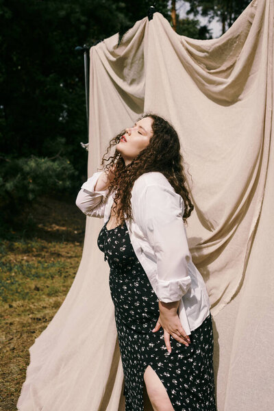 A beautiful plus size woman enjoys her time in a lush field, feeling the warmth of sunlight.
