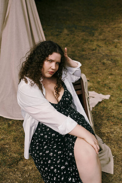 Уверенная в себе женщина plus size отдыхает на солнечном поле, наслаждаясь красотой природы.