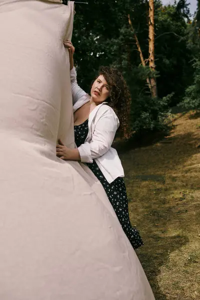 stock image A beautiful plus size woman connects with nature in a vibrant outdoor setting, expressing joy.