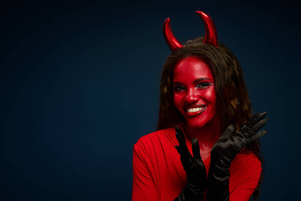The beautiful woman dressed as a devil joyfully expresses excitement for Halloween festivities.