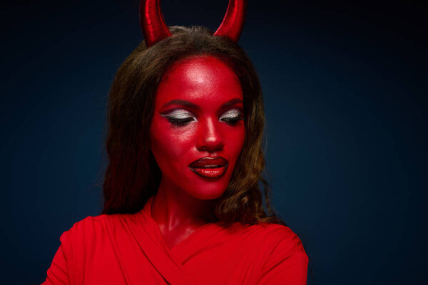 Красивая женщина обнимает дух Хэллоуина, демонстрируя ей очаровательный красный костюм и макияж.