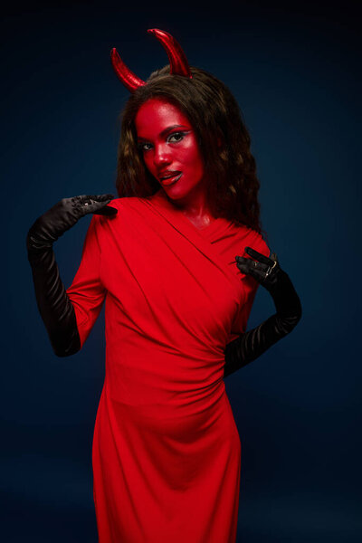 A stunning woman dressed in a striking red costume showcases her playful spirit while posing.