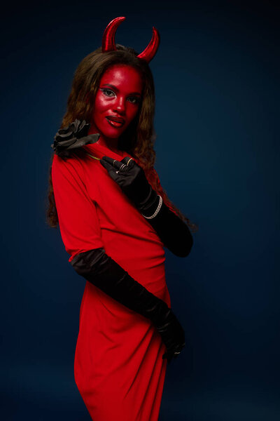 A beautiful woman showcases her unique Halloween costume featuring horns and red attire.