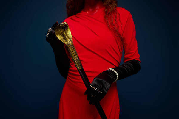 Эта очаровательная женщина, одетая в яркий костюм, элегантно позирует, держа в руках золотой трость..