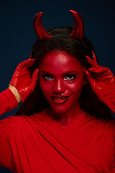 A striking woman in a vibrant red costume poses confidently, embodying Halloween spirit.