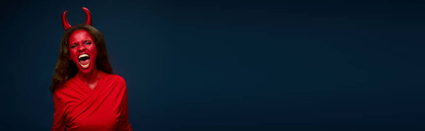 A striking woman in red with devil horns passionately celebrates Halloween.