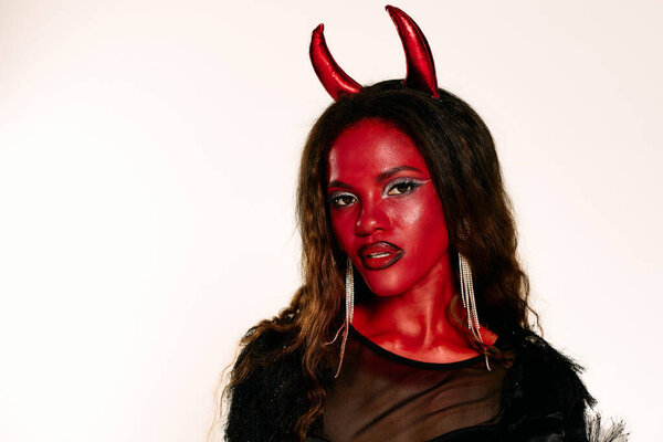 A striking woman showcases her detailed Halloween costume, expressing a playful spirit.