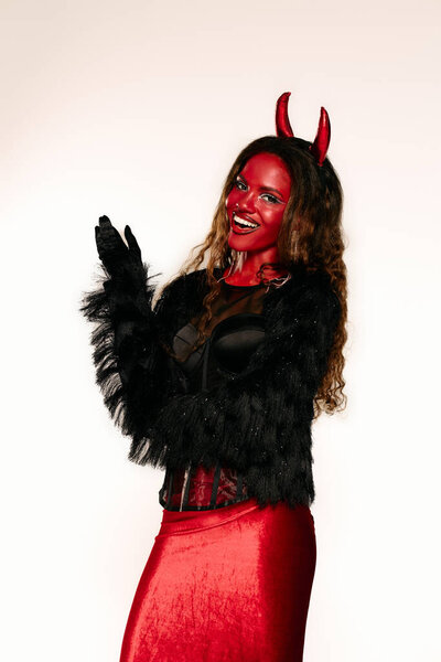 A stylish woman dressed as a devil enjoys the Halloween festivities with a playful attitude.