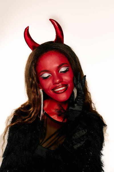 A captivating woman in a devil costume poses, showcasing her vibrant makeup and accessories.