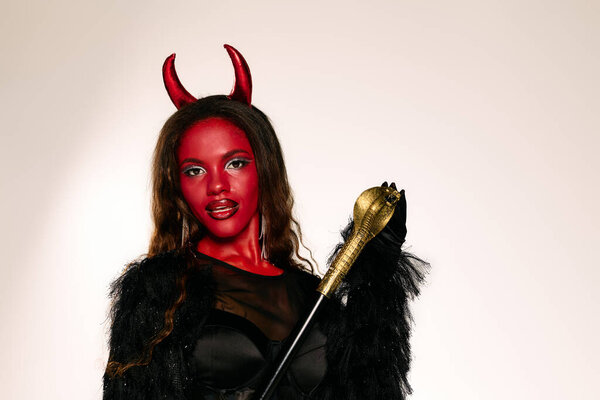 This striking figure wears a bold devil costume with vibrant red makeup and elegant attire.