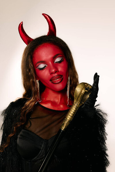 The beautiful woman, adorned in red face paint and horns, captivates with her costume.