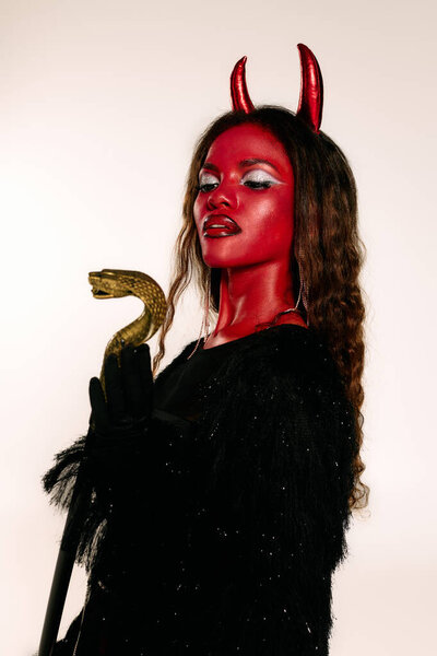 The captivating woman dressed as a devil stands confidently, showcasing her Halloween spirit.