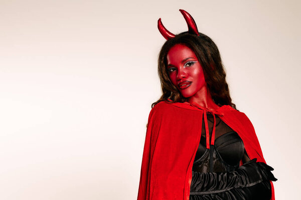 A confident woman in a devil costume showcases her vibrant Halloween spirit.