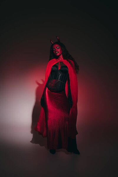 The enchanting woman, adorned in red and black, captivates the night in her Halloween ensemble.