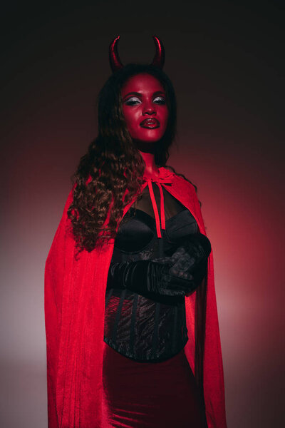 A striking woman in a vibrant red and black Halloween costume showcases her captivating look.