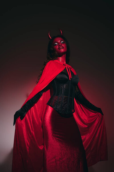Dressed as a devilish character, a woman showcases her stunning costume while posing elegantly.