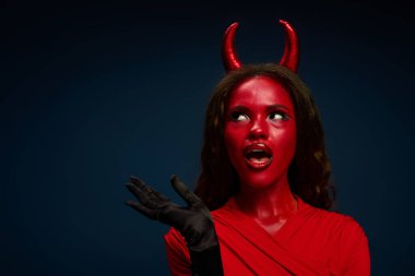 Şeytan kostümü giymiş güzel bir kadın, Cadılar Bayramı neşesini coşkuyla ifade ediyor..