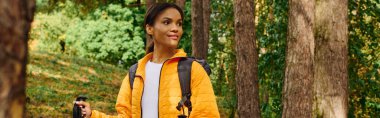 A young African American woman enjoys a peaceful hike through a colorful autumn forest, soaking in nature beauty. clipart