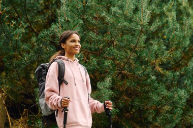 A young African American woman delights in her adventure as she hikes through a colorful autumn forest. clipart