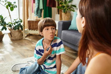 A little boy with hearing difficulties communicates with his mother in a warm environment. clipart