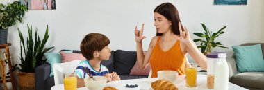 Bir anne kahvaltıda işaret dili kullanarak işitme engelli oğluyla iletişim kuruyor..