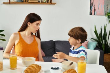 İşitme engelli küçük bir çocuk kahvaltıda annesiyle etkileşime geçiyor..