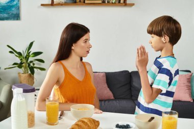 Şefkatli bir anne kahvaltı masasında işitme engelli olan oğluyla meşgul olur..