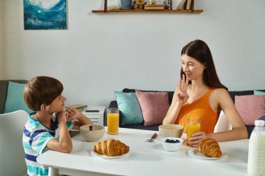 İşitme engelli bir çocuk işaret dili kullanarak annesiyle kahvaltı yapar..