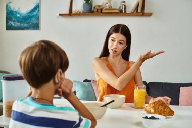 Bir anne kahvaltıda işitme engelli oğluyla rahat yemek odasında konuşur..
