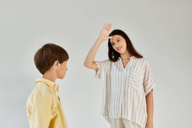 A mother joyfully communicates with her hearing impaired son in a serene environment. clipart