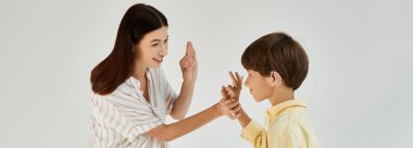 A mother engages playfully with her hearing impaired son, using gestures to communicate. clipart