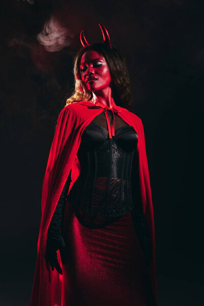 A stunning woman in a devil costume exudes confidence while celebrating Halloween festivities.