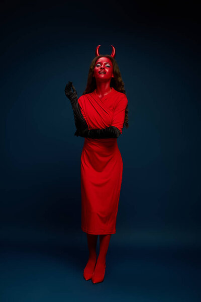 A stunning woman showcases her bold red Halloween costume, embodying a playful yet fierce spirit.