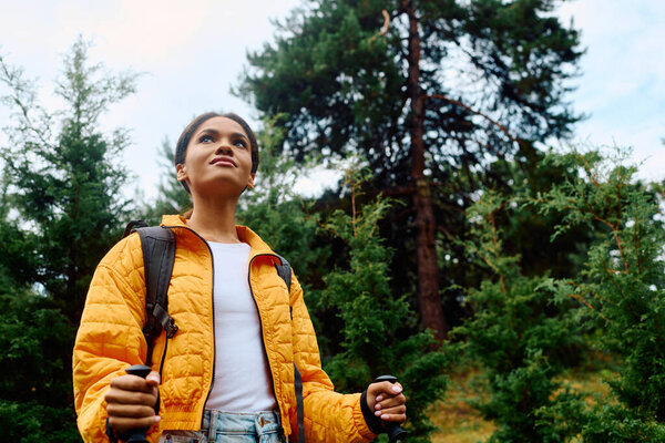 A young African American woman enjoys the vibrant autumn forest, embracing nature beauty and tranquility.