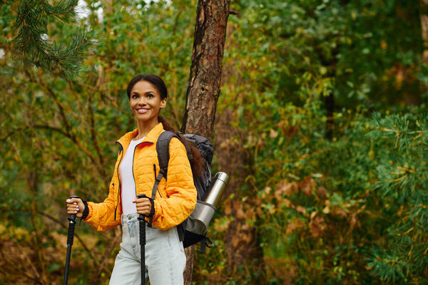 Under the golden hues of autumn, a young woman smiles as she explores the serene forest trails.