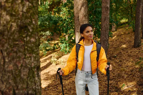 Stock image Amidst colorful autumn foliage, a young woman savors the tranquility of the forest while hiking.