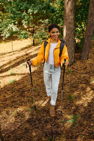 A young woman enjoys her hike in the forest, surrounded by stunning autumn colors and nature beauty.