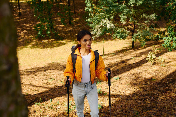 Молодая афроамериканка с энтузиазмом путешествует по красочному осеннему лесу, окруженному природой.