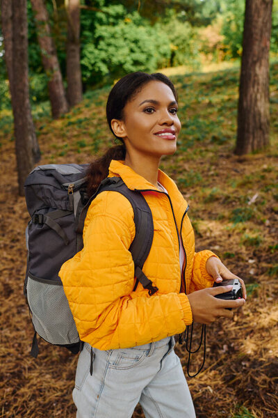 An adventurous young woman explores a colorful forest, surrounded by autumn leaves and nature beauty.