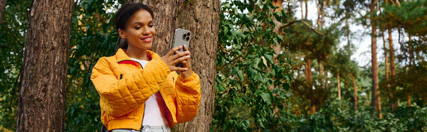 A young woman captures the beauty of autumn on her hike through a lush forest, embracing an active lifestyle.