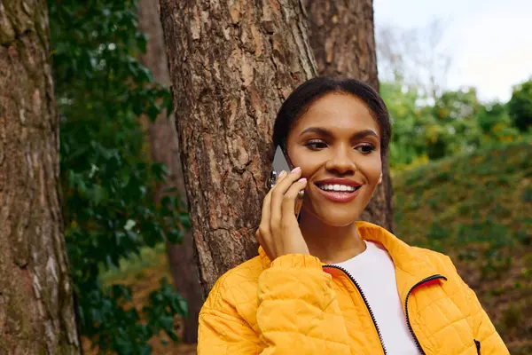 stock image A young woman embraces the beauty of autumn while hiking in a lush forest, connected to nature.