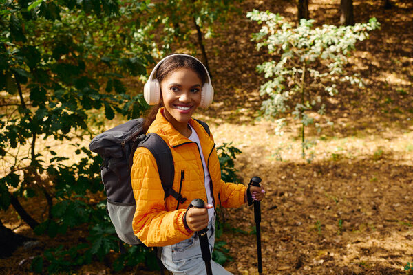 Энергичная молодая женщина увлекается приключениями, путешествуя в красочном осеннем лесу, излучая радость.