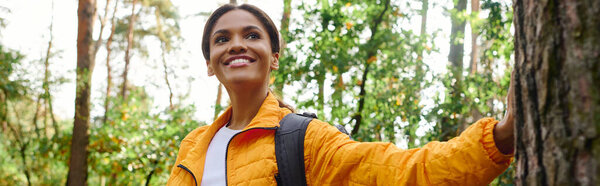 A young woman embraces the beauty of nature while hiking through a colorful autumn forest.
