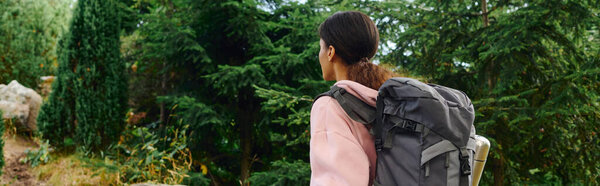 A determined young woman explores vibrant forest paths filled with autumn colors, embracing nature beauty.