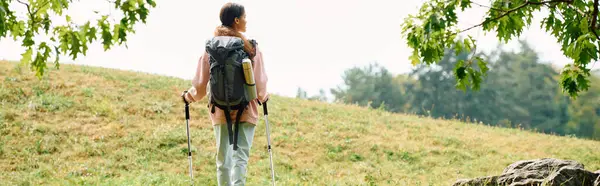 stock image A young African American woman hikes through colorful autumn foliage, fully immersed in nature.