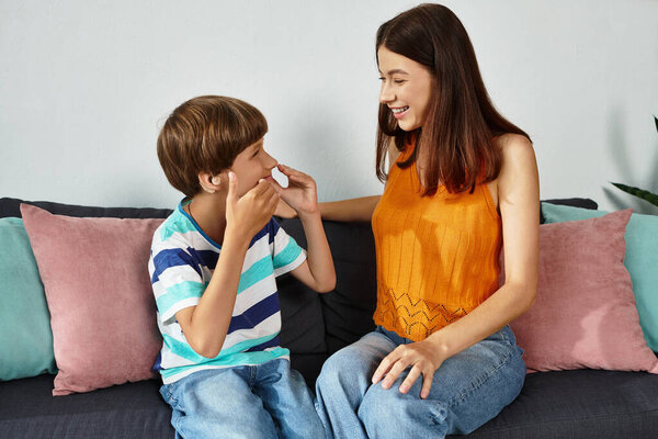 Мать улыбается, когда она взаимодействует со своим сыном, у которого проблемы со слухом, дома.