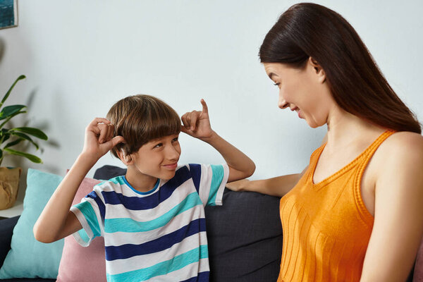 A mother joyfully interacts with her little boy who has a hearing impairment.